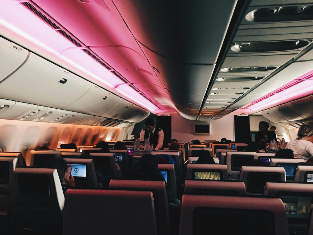 Interior view of an airplane cabin at night with passengers and ambient lighting.